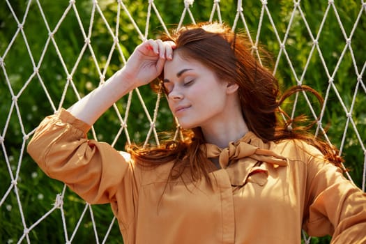 a close horizontal photo of a beautiful woman lying in a hammock with her eyes closed enjoying a rest. High quality photo