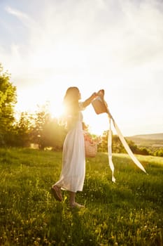 a woman in a light dress is happily spinning in nature, holding a hat in her hands, illuminated from the back by the sun. High quality photo