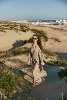 a woman on vacation walks along the promenade in a long dress and sunglasses. High quality photo