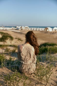 a woman sits with her back to the camera on the sea coast enjoying the sea view. High quality photo