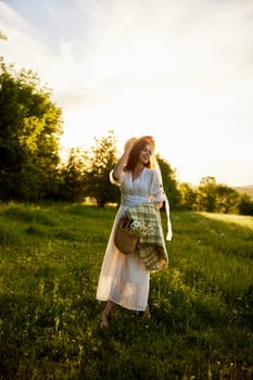 a woman in a wicker hat walks through the forest and looks towards the sunset holding a plaid and a bag in her hands. High quality photo