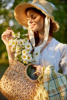 close portrait of a beautiful woman in a wicker hat and with a plaid in her hands holding a basket of daisies. High quality photo