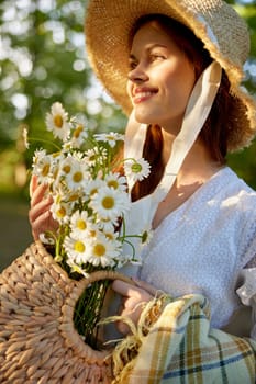 close portrait of a beautiful woman in a wicker hat and with a plaid in her hands holding a basket of daisies. High quality photo