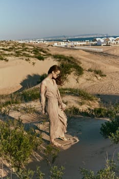 a slender woman in a long dress walks along a wild beach alone. High quality photo