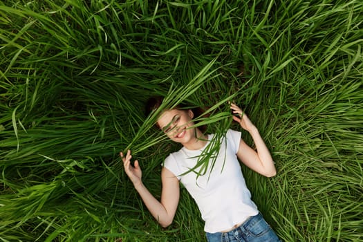 happy woman lying in tall grass biting leaves. High quality photo