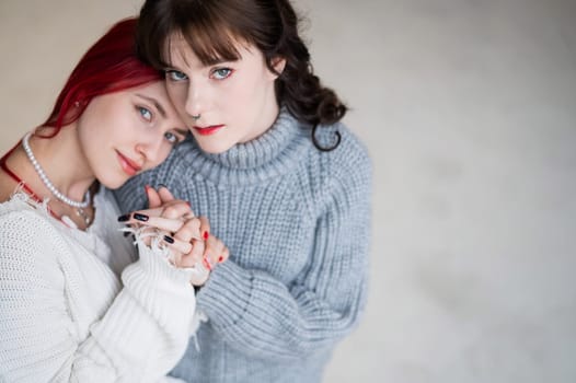 Portrait of two tenderly hugging women dressed in sweaters. Lesbian intimacy