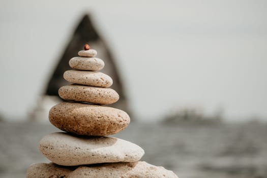 Pyramid stones on the seashore with warm sunset on the sea background. Happy holidays. Pebble beach, calm sea, travel destination. Concept of happy vacation on the sea, meditation, spa, calmness.