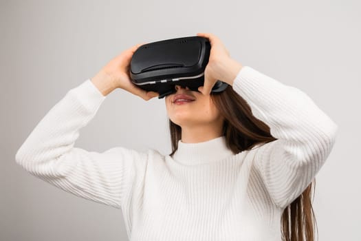 Amazed young girl in virtual reality using VR glasses headset explores metaverse on the white background