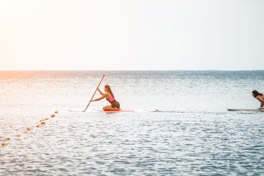 Sea woman and man on sup. Silhouette of happy young woman and man, surfing on SUP board, confident paddling through water surface. Idyllic sunset. Active lifestyle at sea or river
