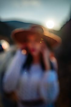 Woman road mountain. A woman in a white sweater, black boots and a hat walks along a winding alpine path between the mountains at sunset in late summer. The concept of travel