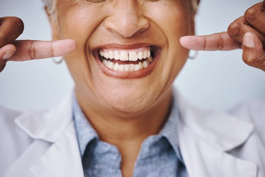 Dental, hand and pointing by elderly woman in studio for mouth, hygiene or denture care on grey background. Teeth whitening, cleaning and senior lady happy for oral, tooth and natural looking veneers.