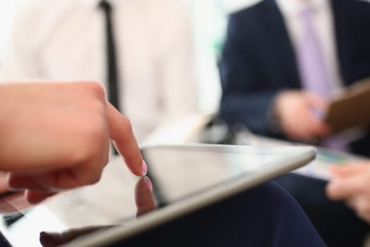 Woman holds tablet in hands and explains information to colleague. Concept of teamwork and business application