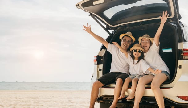 Family Day. Happy people having fun in summer vacation on beach, Family traveling in holiday at sea beach, Dad, mom and children daughter enjoying road trip sitting on family back car raise hand up