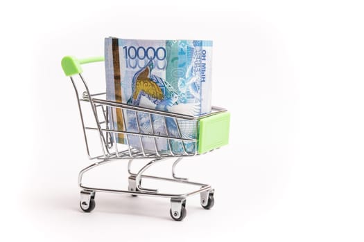 10000 banknotes of Kazakhstani tenge in a shopping cart isolated on a white background.