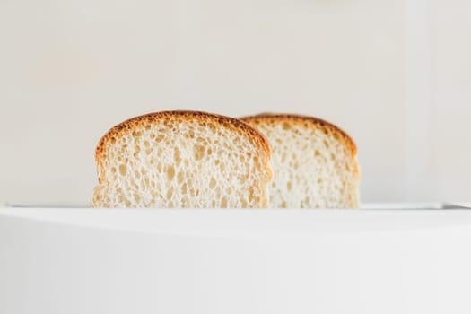 Front view on sliced fresh bread inserted into a white toaster, selective soft focus, copy spce.