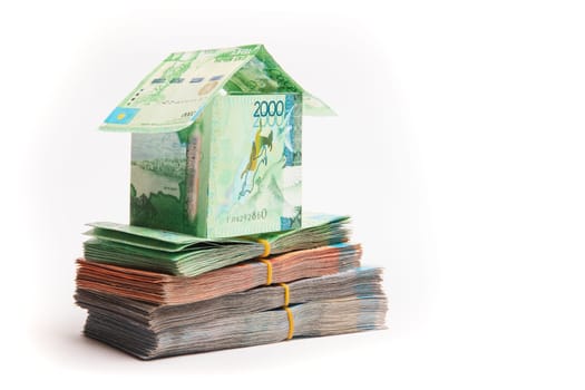 House made of banknotes of Kazakh money stands on packs of tenge. Mortgage concept, real estate appreciation, copy space.