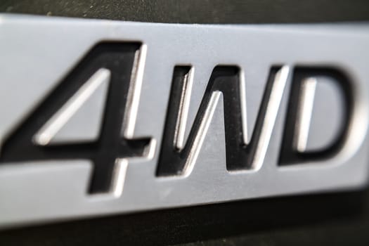 The inscription 4WD close-up on the nameplate of an SUV, selective soft focus.
