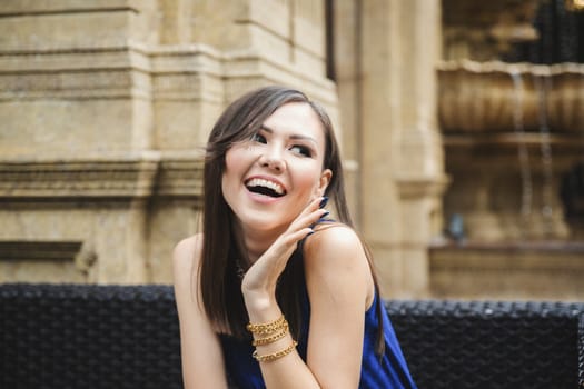 Pleasantly surprised young woman looking away while sitting in a street cafe.