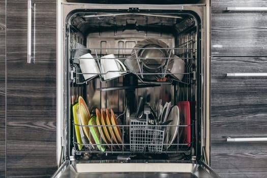 Open dishwasher with dishes built into the kitchen.