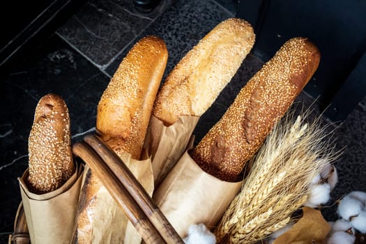Fresh bakery products in the form of four loaves in degradable paper eco-packaging and a bouquet of wheat in a wicker basket.