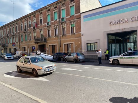 Cremona, Italy - 18th April 2023 just rolled over crashed car after an accident, police officer helping with traffic
