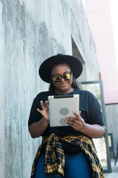 Beautiful African American woman using digital tablet, watching movie outdoors. Successful blogger influencer streaming video, communication online