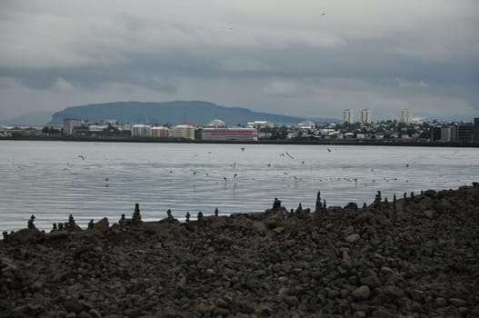 Stone towers on the shore in Reykjavik, Iceland with flock of birds flying by