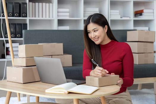 SME entrepreneur Small business entrepreneurs Online selling ideas, Happy Young Asian business owner work on computer and a boxes at home, delivery SME procurement package box deliver to customers.