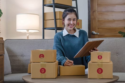 Portrait young attractive asian female owner startup business work happy with box at home prepare parcel delivery in sme supply chain, start up small business concept...