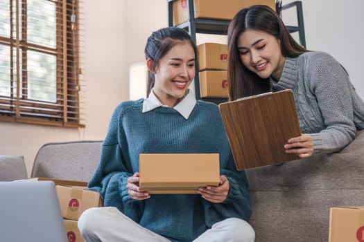 Two Asian Young business woman on sofa at home. startup sme small business entrepreneur SME distribution warehouse with parcel mail box. SME Online marketing and product packaging and delivery service..