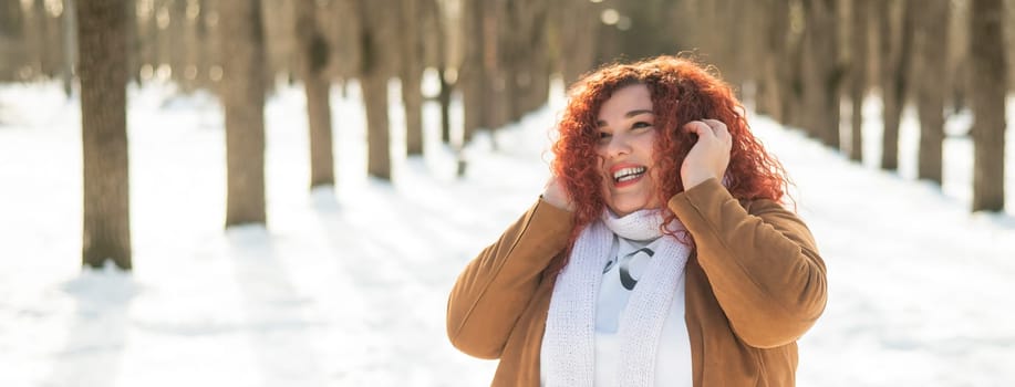 A plump woman listens to music in headphones while walking in the park in winter