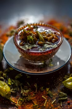 Close-up shot of fresh Indian Lunchtime dish luffa or Galka nu Shaak in a glass container along with all its ingredients on a rust-colored surface.