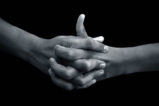 Shot of a human hand showing Linga mudra with interlocked fingers and thumb coming out of it isolated on black background.