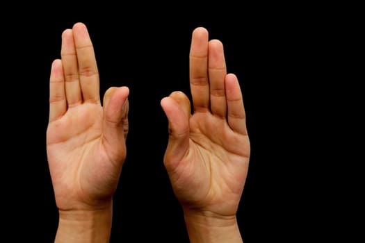 Hands in Vayu Mudra isolated on a black background.