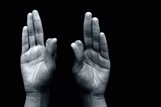 Hands in Vayu Mudra isolated on a black background.