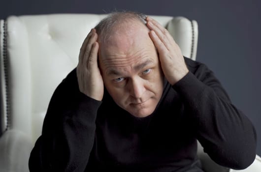 The man is concerned about the problem of hair loss and baldness. He examines his hair on his head.