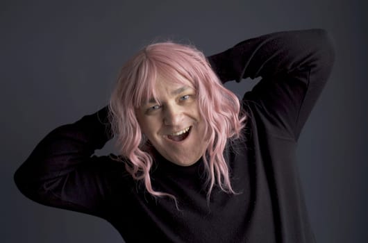 Portrait of a man in a pink wig, looking at the camera, grimacing, posing. close-up.