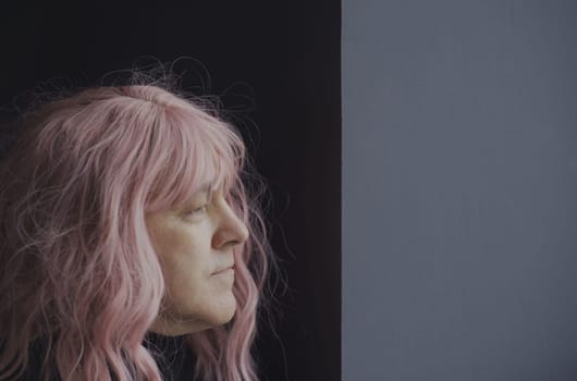 Portrait of a man in a pink wig looking out the window. Side view. Close-up.