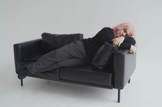 A man in a pink wig is sleeping on the couch. White background.