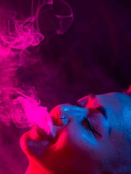 Asian woman with short haircut smoking in neon light. close-up portrait