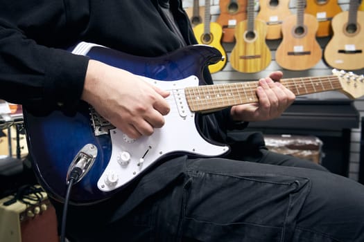 The guitarist plays a guitar in a guitar store