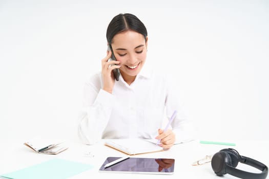 Portrait of smiling woman entrepreneur talking with her client on mobile phone, speaking with someone on cellphone, white background.