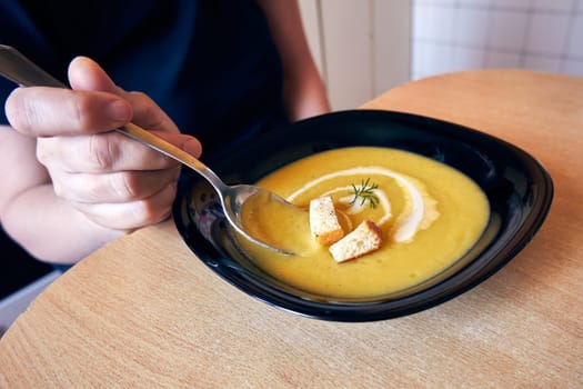 Vegetarian food. Soup puree in a bowl on the table. Woman eating mashed vegetable soup