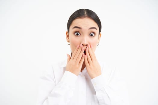 Portrait of asian businesswoman looks surprised, amazed reaction on advertisement, stands over white background.