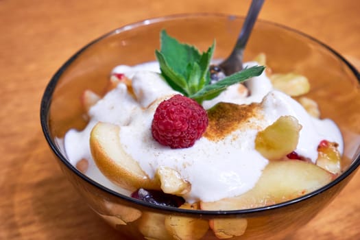 Fruit salad with yogurt in a transparent plate on the table close-up