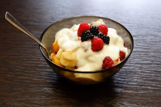 Fresh delicious fruit salad with yogurt on a wooden table