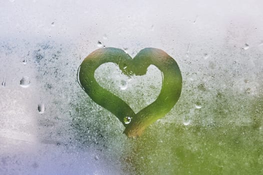 Heart drawn on the misted glass. Drawing a heart on a window with raindrops