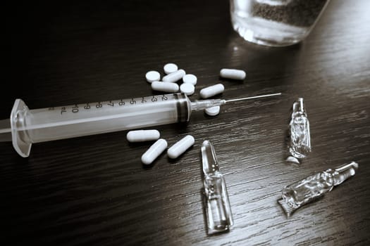 Medical syringe, ampoules and pills on the table. Selective Focus