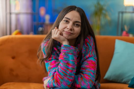 Portrait of happy calm Caucasian woman at home couch smiling friendly, glad expression looking away dreaming resting, relaxation feel satisfied concept good news, celebrate win. Young girl in room