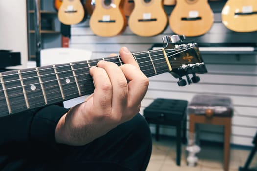 Ryazan, Russia - October 9, 2022: Musician playing guitar in a guitar shop. Buying a guitar from a guitar shop